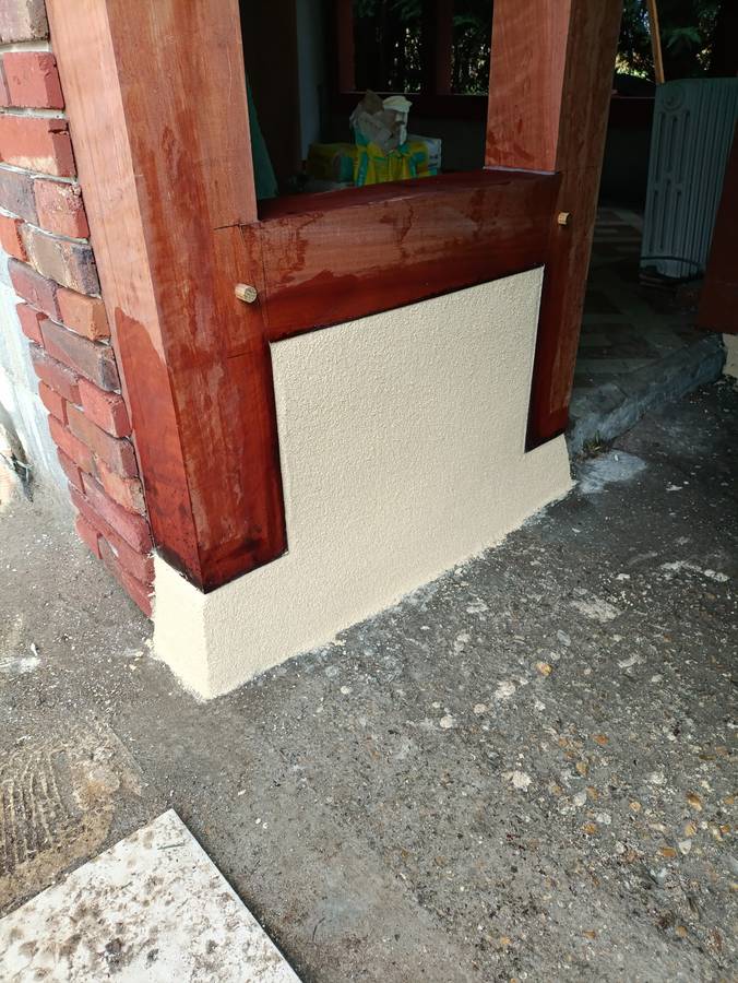 Détail de soubassement : enduit, brique et bois traité