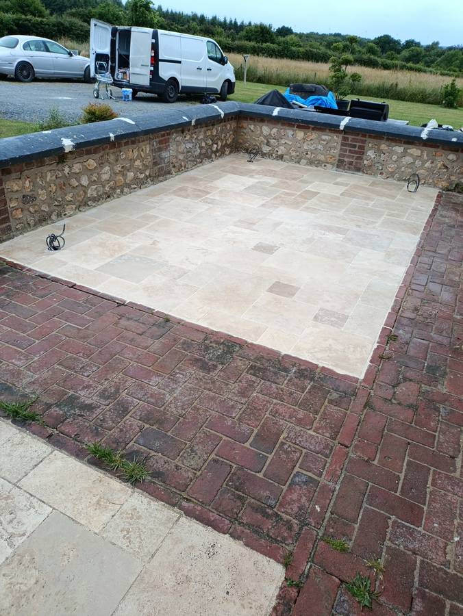 Terrasse en travertin posée dans un muret de silex existant